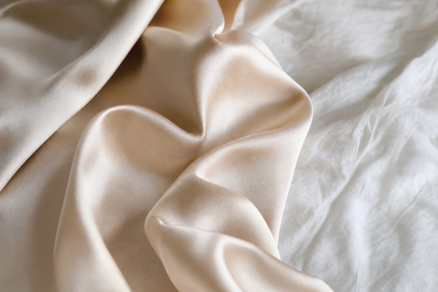 Seta ipoallergenica: dettaglio della seta di gelso su letto di lino con luce naturale, la fibra liscia e traspirante che rispetta la pelle